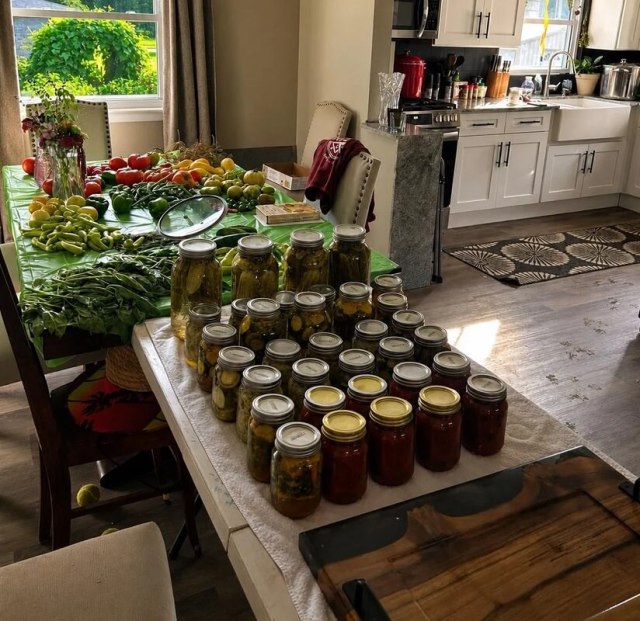 A colorful array of fresh vegetables including tomatoes, cucumbers, peppers, and green beans on a green tablecloth.