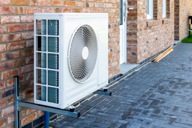 An outdoor air conditioning unit mounted on a brick wall.