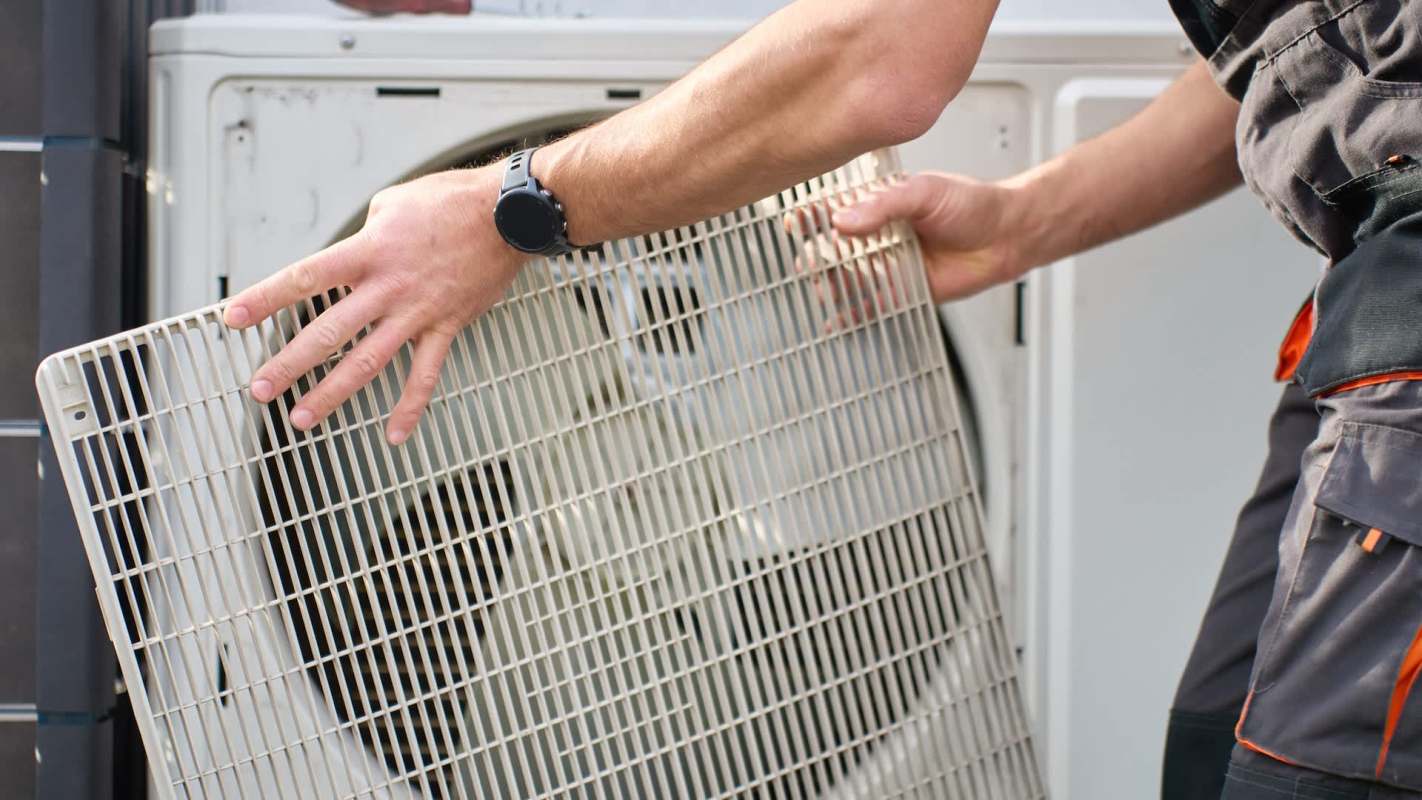 A person putting a cover on an HVAC fan.
