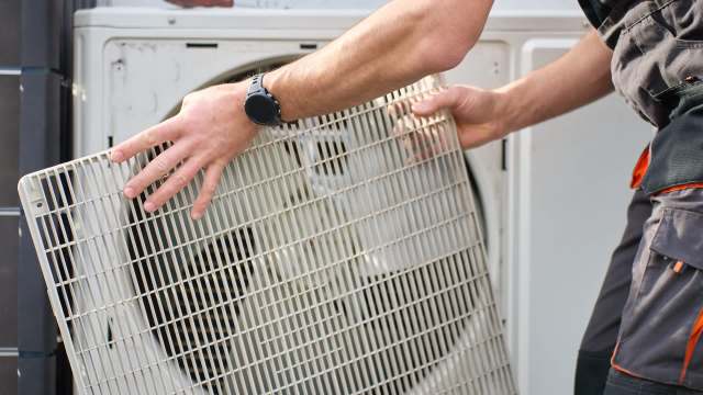 A person putting a cover on an HVAC fan.