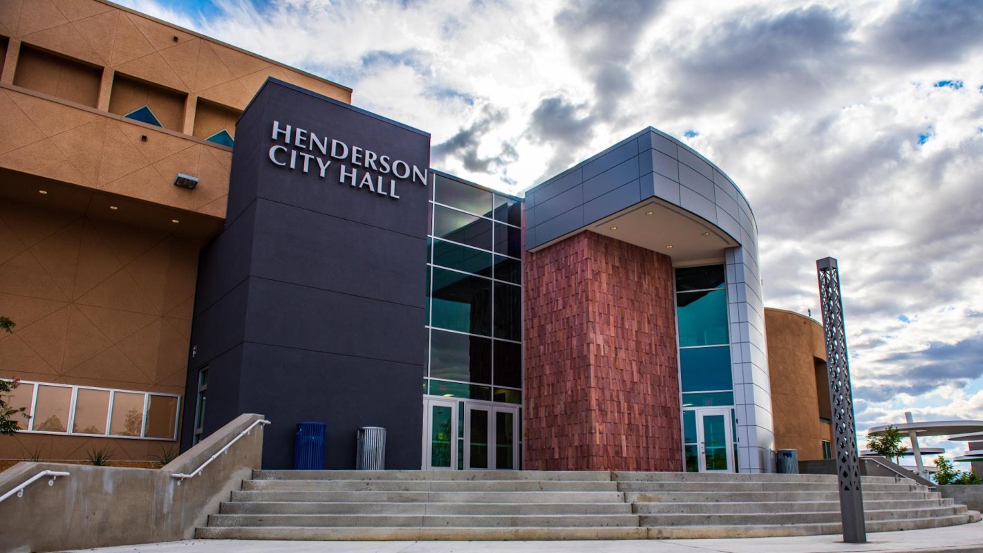 A modern city hall building with large glass windows and angled architecture under a cloudy sky.