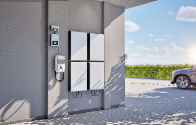 A wall-mounted electric vehicle charger beside energy storage units.