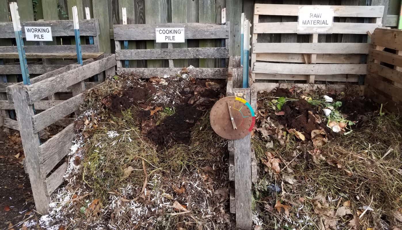 A composting system with labeled piles and a temperature gauge.