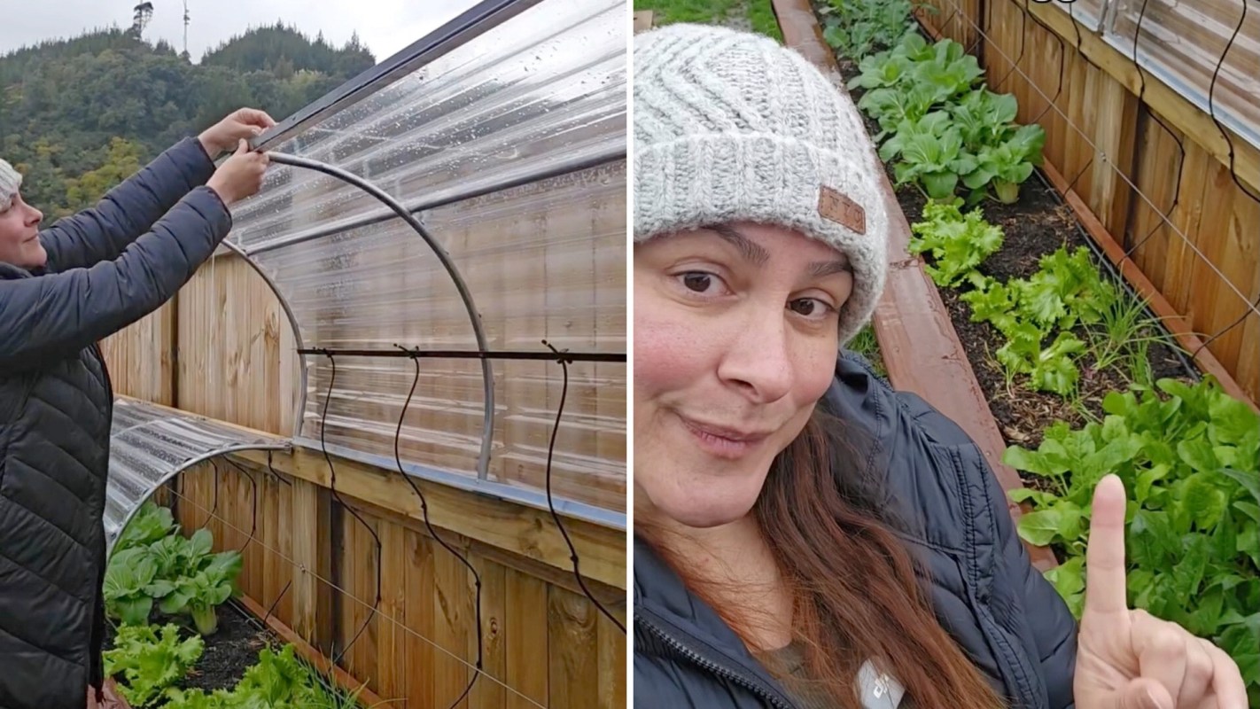 A woman in a gray beanie adjusts protective covers in a garden.