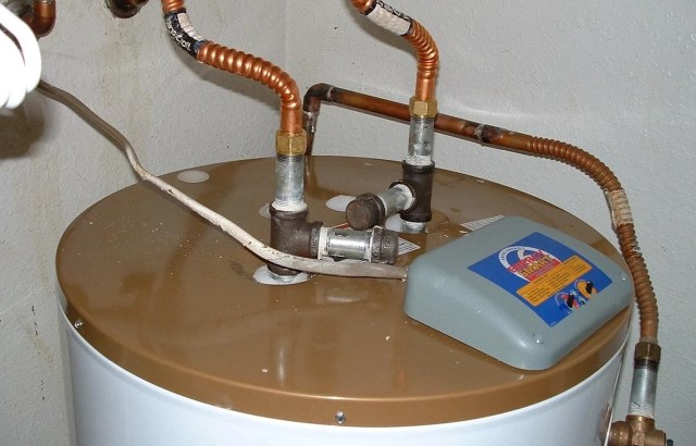 A water heater with copper pipes and a control unit on top.