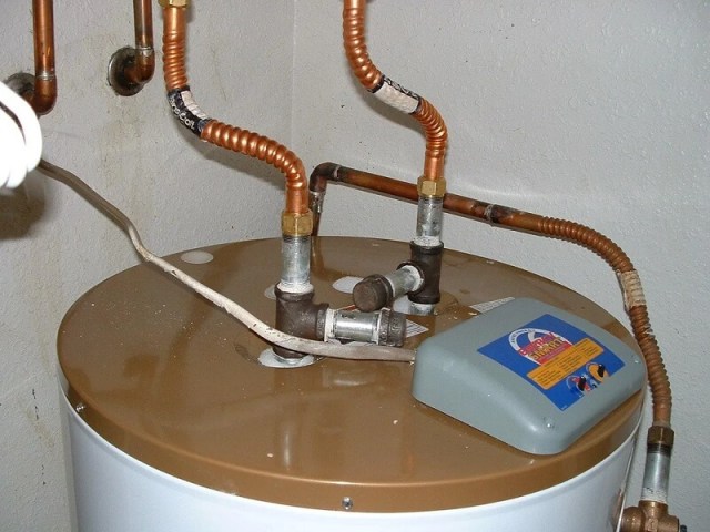 A water heater with copper pipes and a control unit on top.