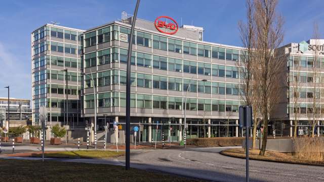 A modern office building with large glass windows and signage for BYD, surrounded by a landscaped area.