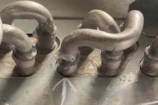 Close-up view of metallic pipes with a welded joint on a metallic surface, showing some moisture.