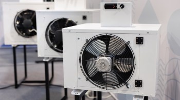 Three air conditioning units are displayed on stands, featuring visible fans and control panels.