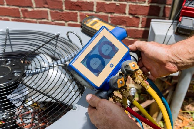 A worker doing maintenance on an HVAC unit.