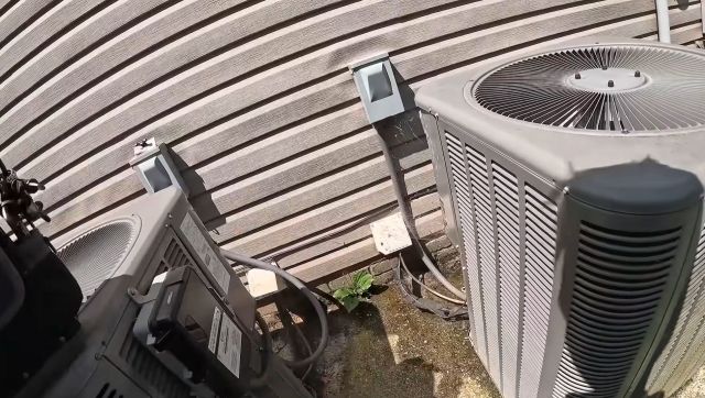 An HVAC unit behind a house.