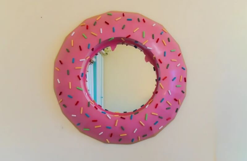 A mirror decorated like a pink donut with sprinkles.