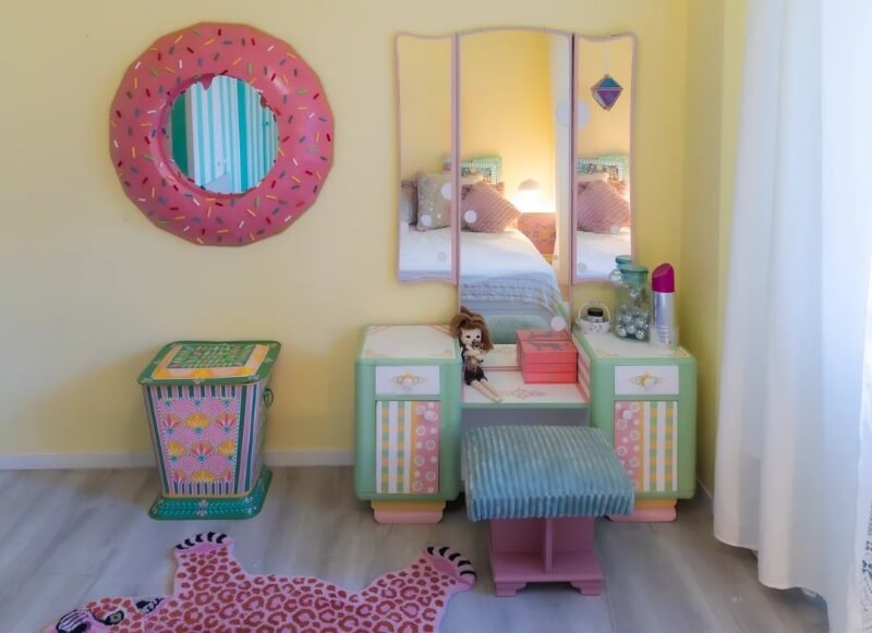 A mirror in a bedroom decorated like a pink donut with sprinkles.