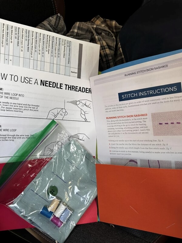 Thread, material and a button in a plastic bag on top of instructions for stitching.