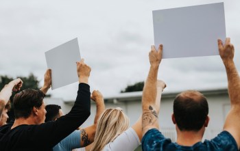 A group of people raising blank signs in the air during a protest or demonstration.