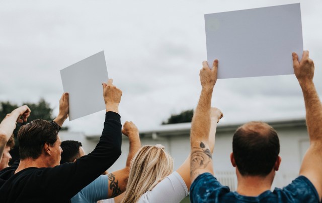 A group of people raising blank signs in the air during a protest or demonstration.