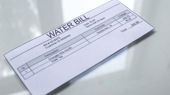 A printed water bill with details including charges, due date, and customer information.
