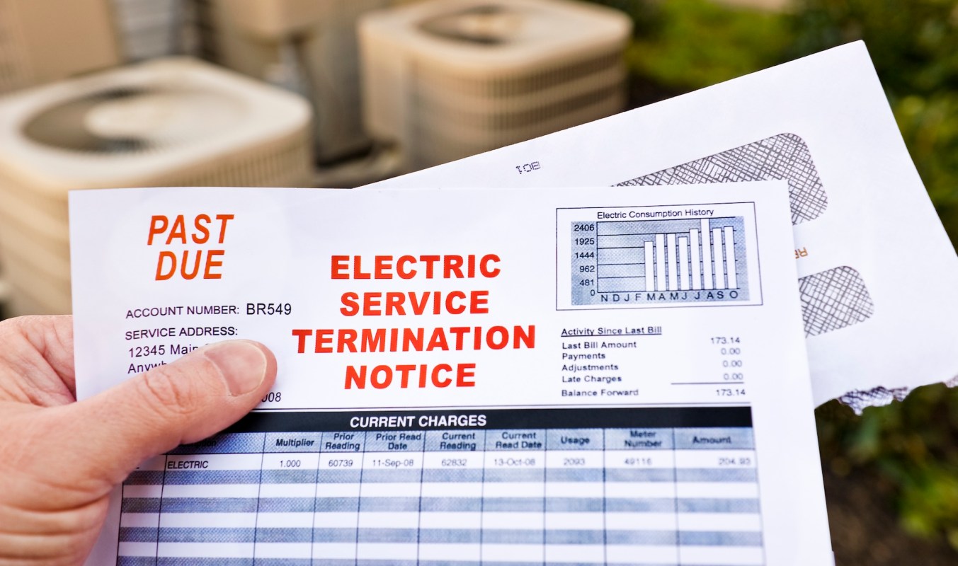 A person holding a past due electric service termination notice with account details and payment history.
