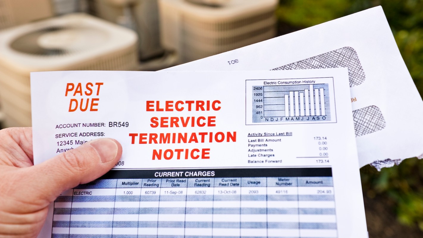 A person holding an overdue bill and electric service termination notice.