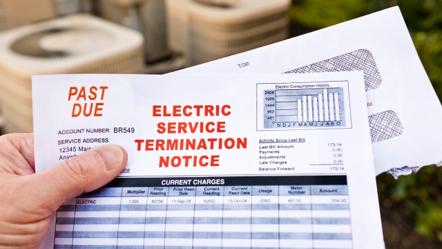 A person holding an overdue bill and electric service termination notice.