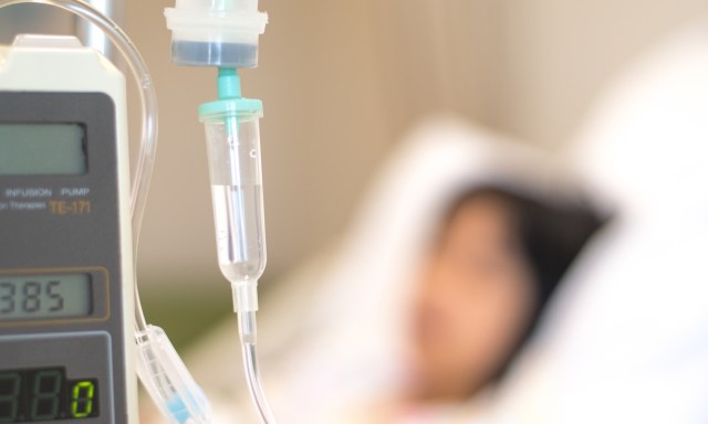 An IV drip and medical device monitoring a patient in a bed.