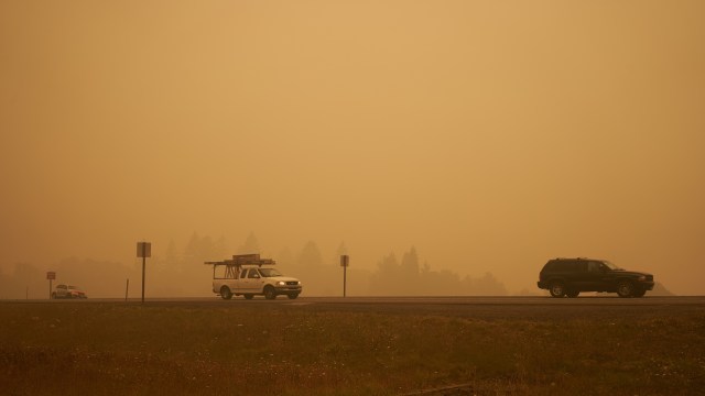 Vehicles on a road shrouded in smoke.