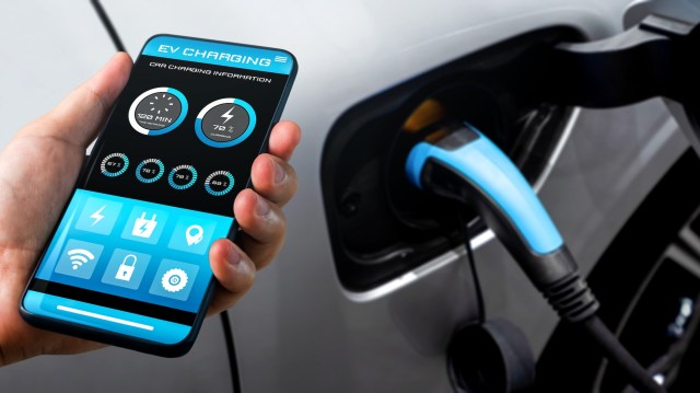 A person using a smartphone to monitor EV charging information.