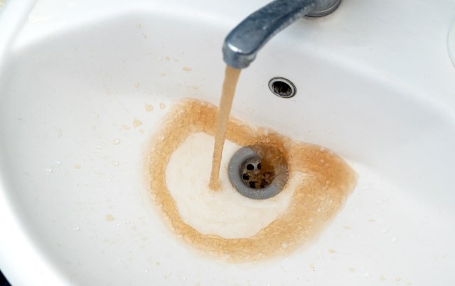 A running faucet with brown water.