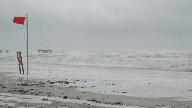A stormy beach with a red flag hurricane warning.