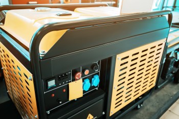 A close-up of a yellow and black industrial generator control panel with various switches and ports.