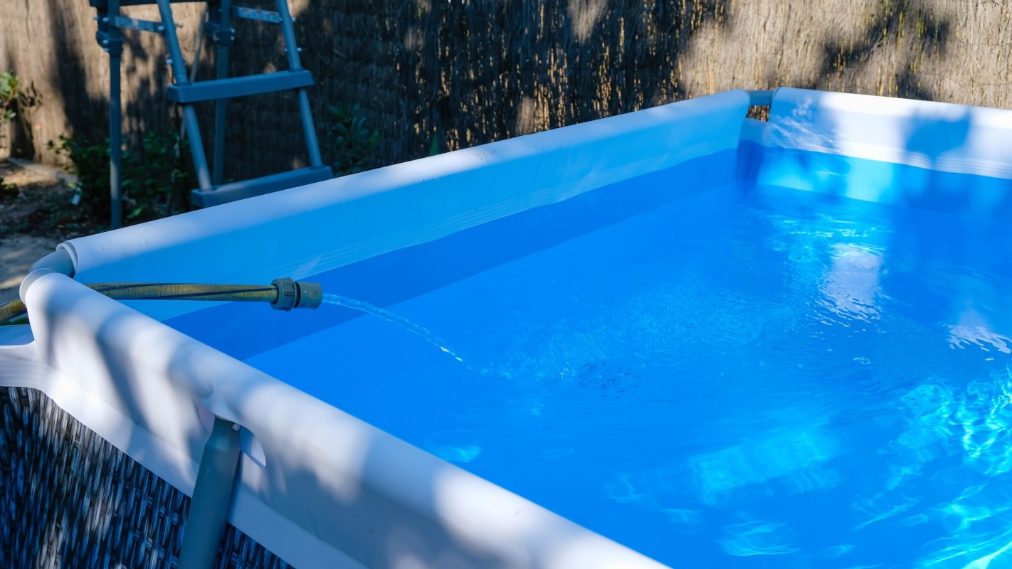 A pool being filled with water from a hose.