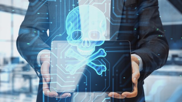 A person holding a tablet behind a digital skull and crossbones.