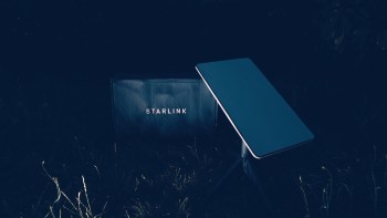 A Starlink dish and router in a dark outdoor setting.