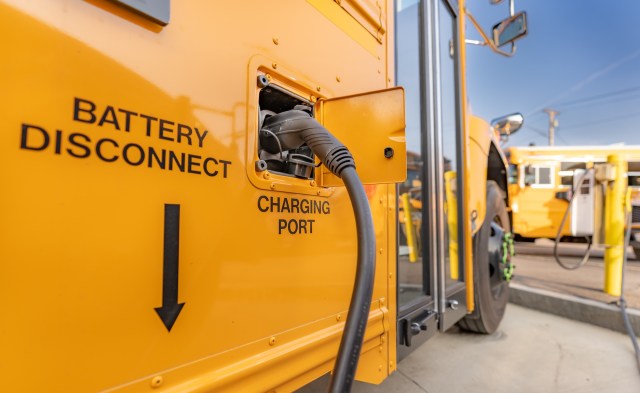 A close-up of an electric school bus's charging port alongside battery disconnect instructions.