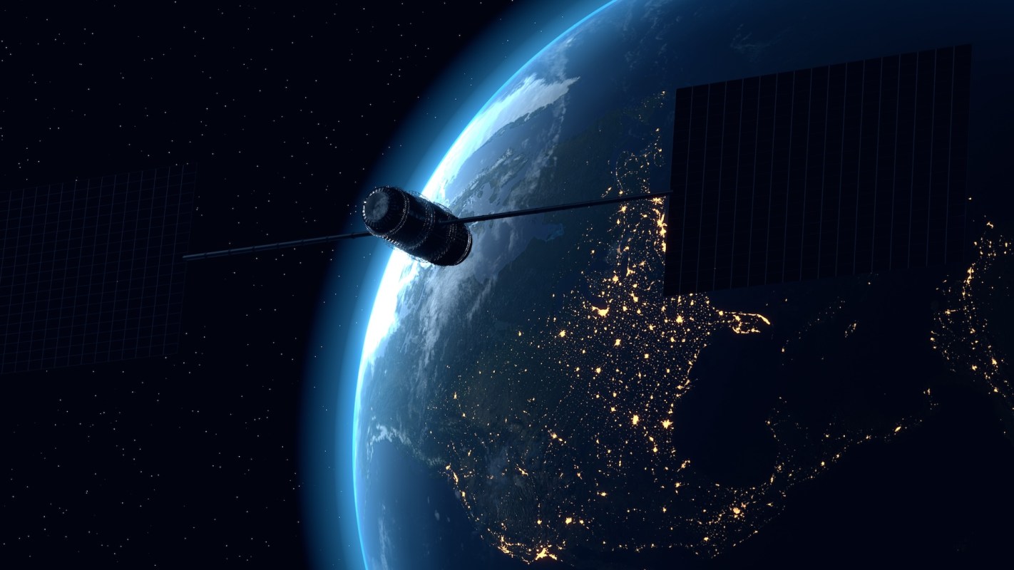 A satellite orbits Earth, with visible city lights and natural features in the background.