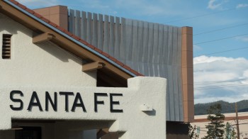 A close-up of a building sign that reads "SANTA FE" with modern architecture in the background.