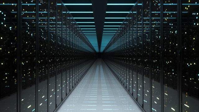 A narrow corridor lined with illuminated server racks.