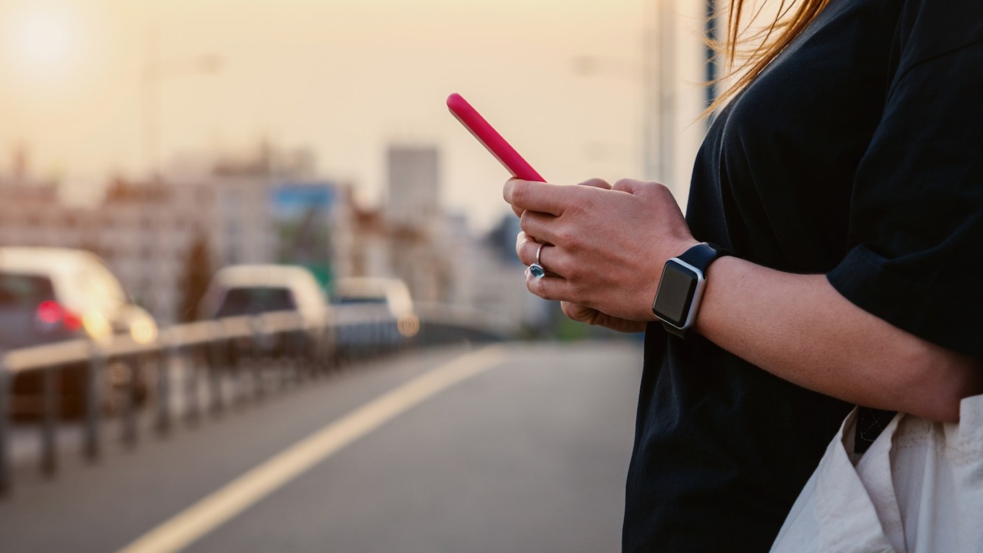 A person on a phone near traffic.