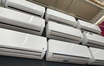 A row of white mini-split units displayed on a wall in a store.