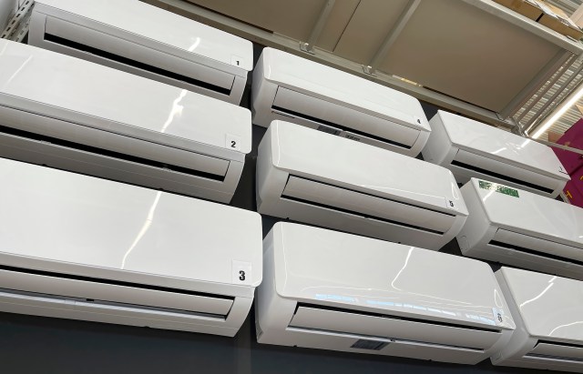 A row of white mini-split units displayed on a wall in a store.