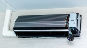 A ceiling-mounted mini-split air unit with an exposed ventilation grill and electrical components visible.