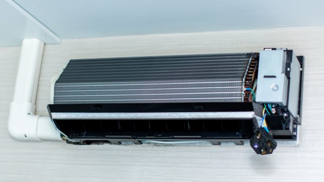 A ceiling-mounted mini-split air unit with an exposed ventilation grill and electrical components visible.