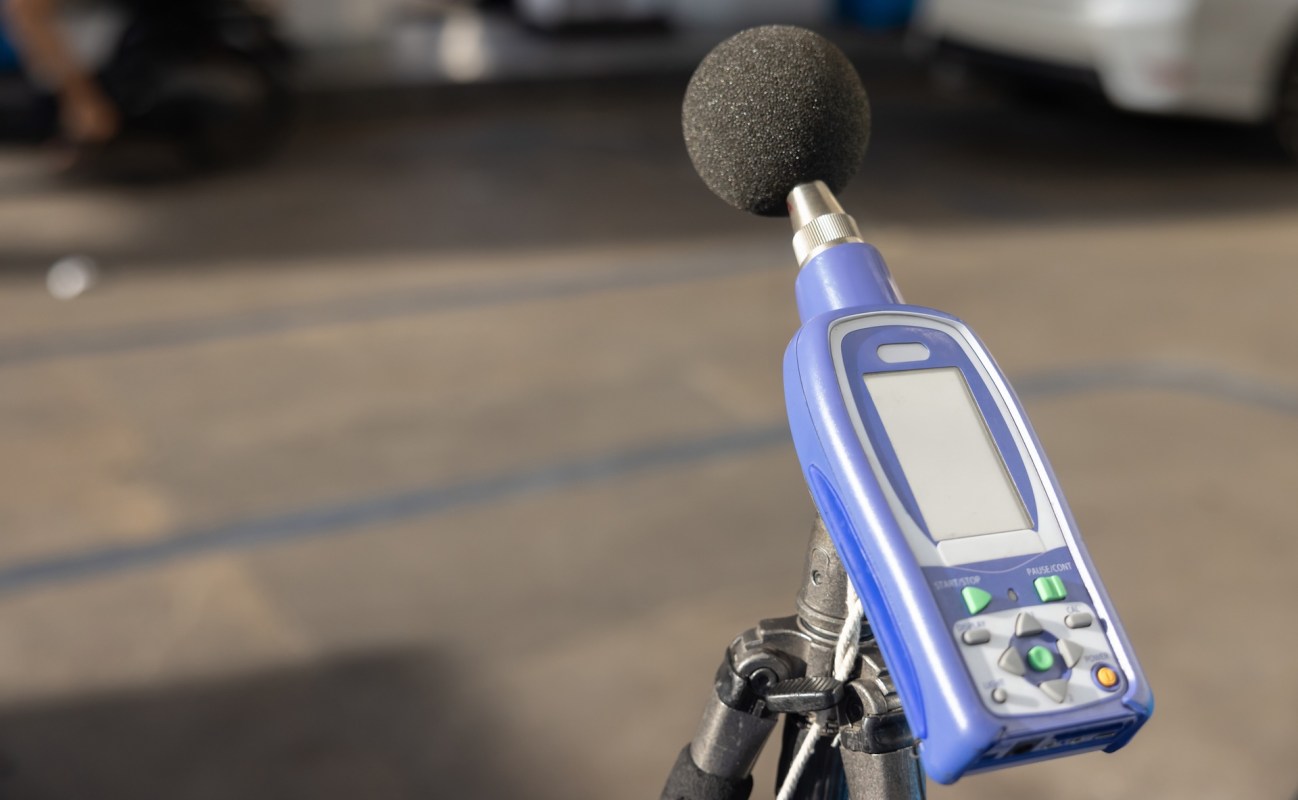 A handheld sound level meter with a microphone placed on a tripod.