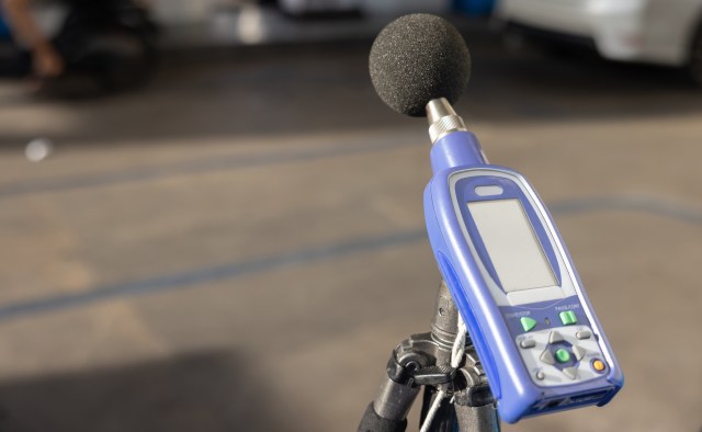 A handheld sound level meter with a microphone placed on a tripod.