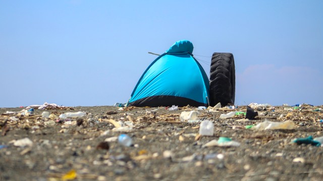 A blue tent on a littered beach.