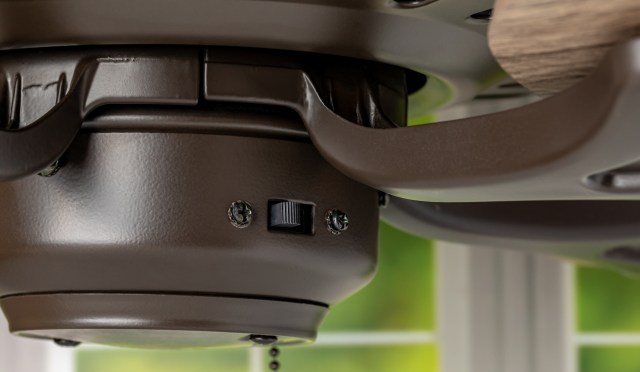 A close-up view of a brown ceiling fan motor with a switch and visible screws.