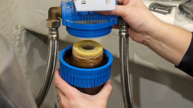 A person is assembling a blue water filter device with a visible filter cartridge inside.