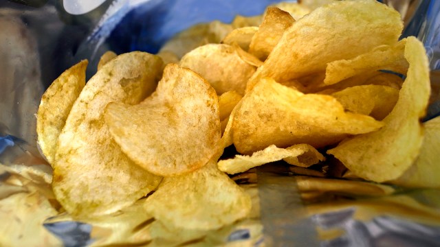 A close-up of golden, crispy potato chips inside a shiny bag.