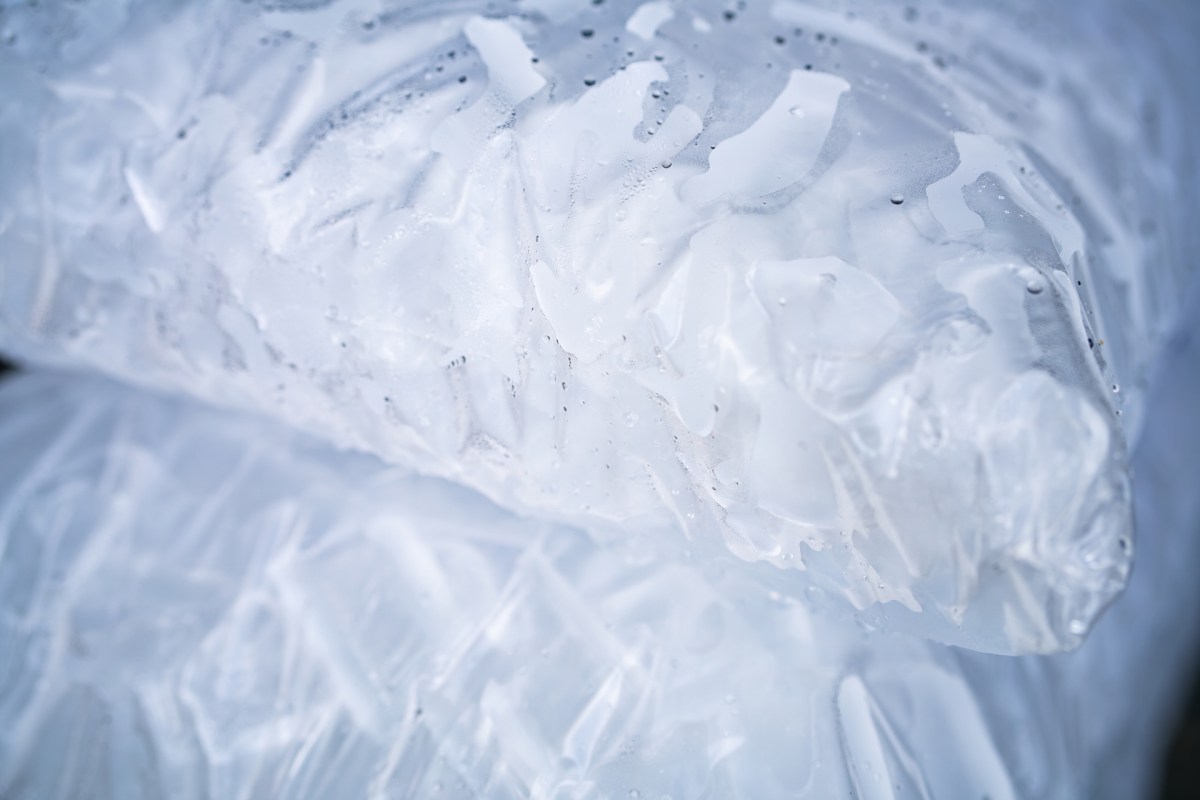 Close-up of ice cubes in a clear plastic bag with a textured surface, glistening and slightly moist.