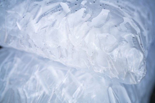 Close-up of ice cubes in a clear plastic bag with a textured surface, glistening and slightly moist.